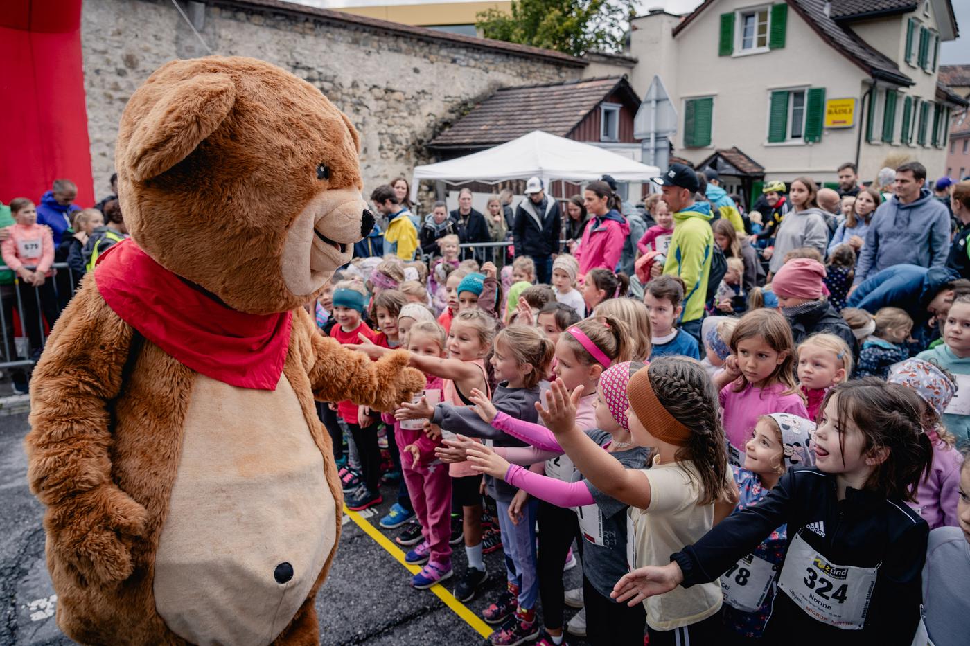 Bärenmaskottchen begrüsst Kinder beim Start eines Laufevents
